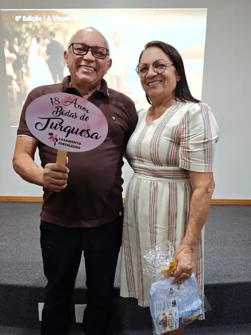 Casal da Viagem das Bodas segurando a plaquinha de 18 anos de casados, Bodas de Turquesa
